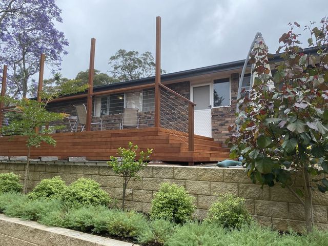 Finished raised hardwood deck with a wire balustrade above a garden