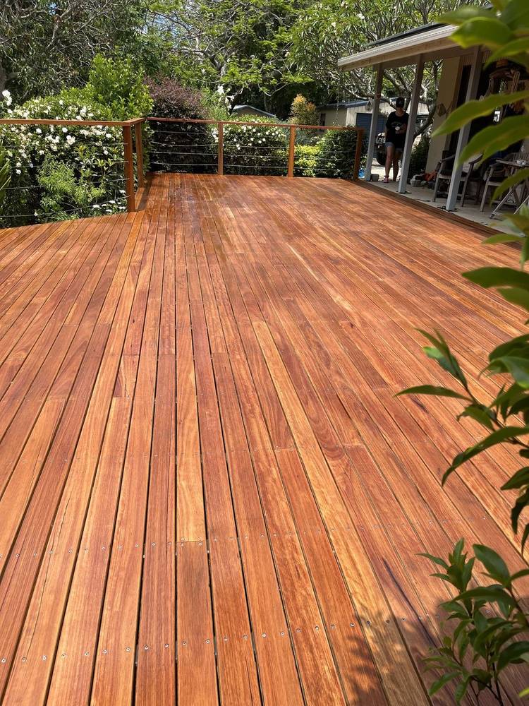 Oiled hardwood deck with a timber and wire balustrade in a garden