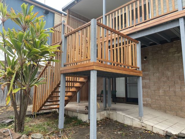 Timber stairs with a landing and a timber balustrade running up to a deck