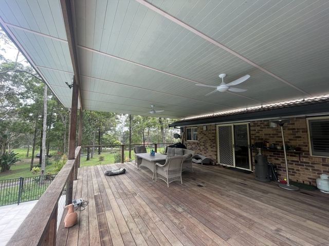 Under a finished covered deck with a lined roof and ceiling fan
